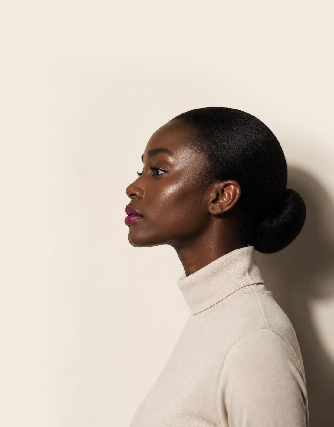 Profile portrait of a woman with a sleek low bun and a fuchsia lip